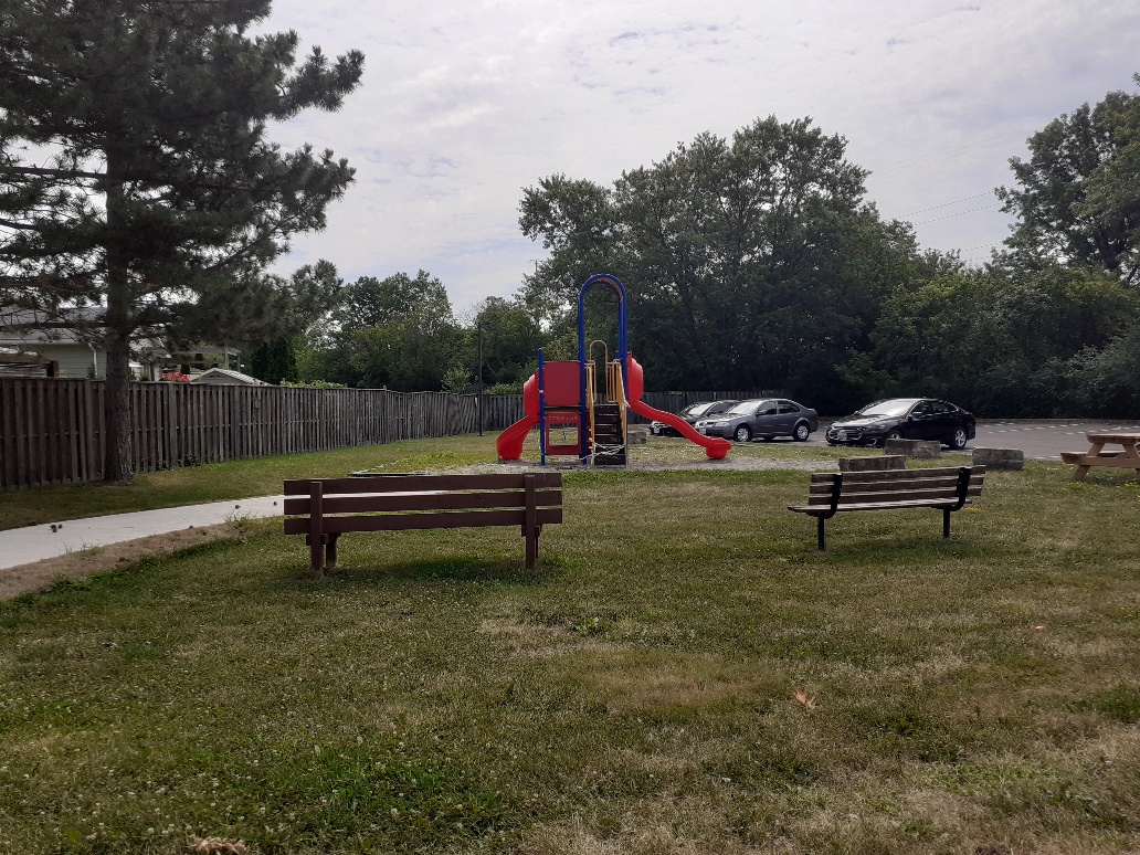 Playground with benches next to a parking lot