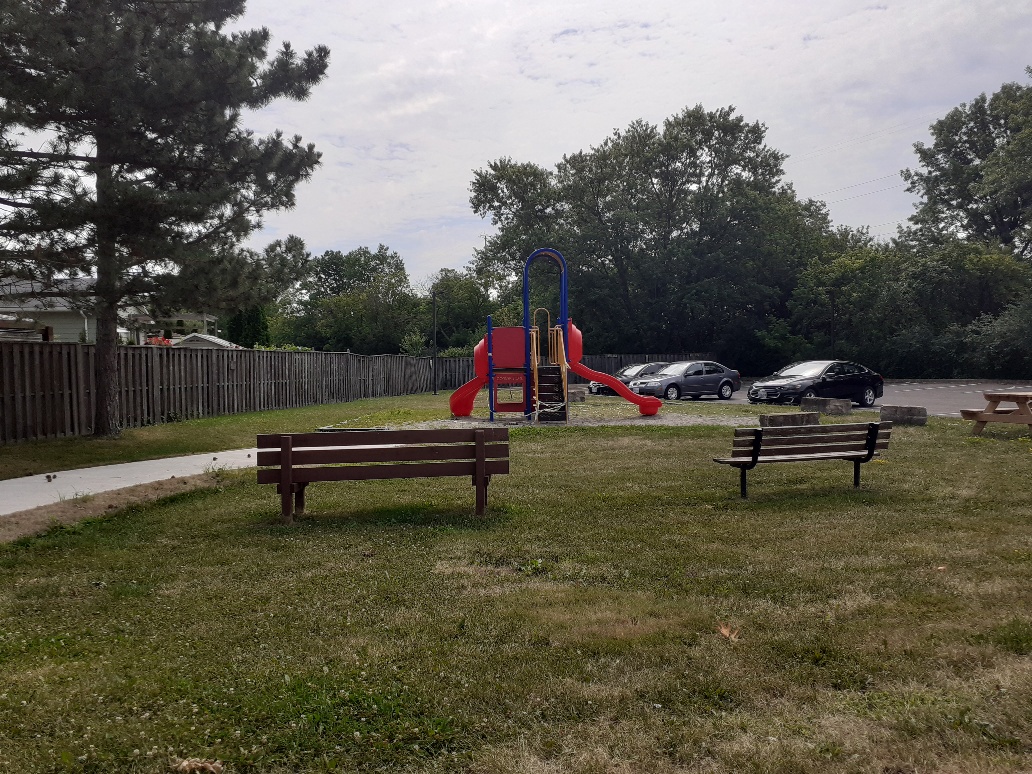 Playground with benches next to a parking lot